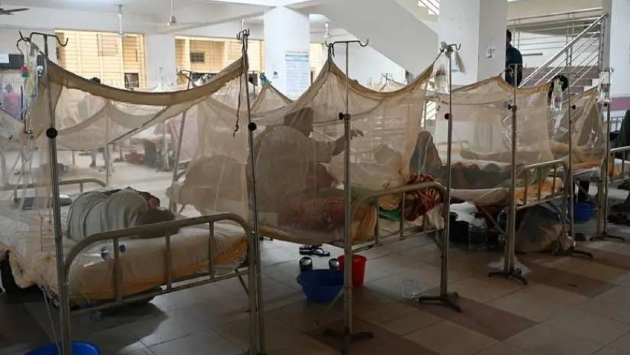 একটি হাসপাতালের ডেঙ্গু ওয়ার্ডে বিছানায় মশারি টানিয়ে শুয়ে ও বসে আছেন রোগীরা