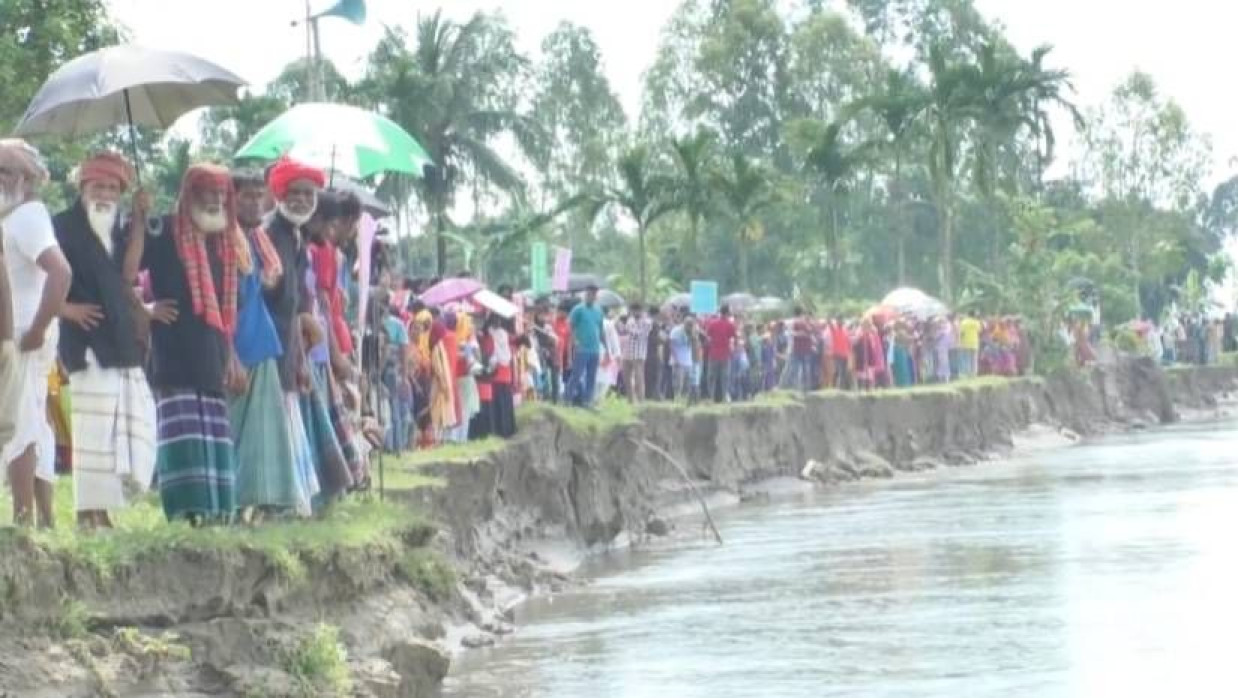 নদীর তীরে স্থানীয় লোকজনের মানববন্ধন