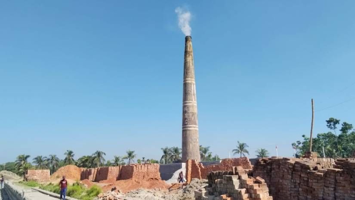 একটি ইটভাটার চিমনি থেকে ধোঁয়া উড়ছে