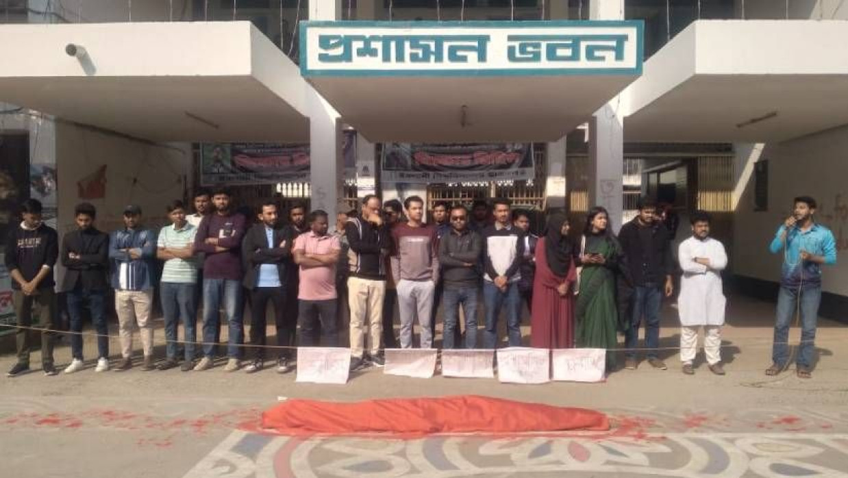 বিশ্ববিদ্যালয়ের প্রশাসন ভবনের সামনে প্রতীকী লাশ রেখে প্রতিবাদ কর্মসূচি পালন করেন শিক্ষার্থীরা