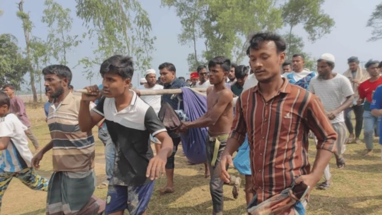 আহত মোহাম্মদ হানিফকে উদ্ধার করে নিয়ে যাচ্ছেন স্থানীয়রা