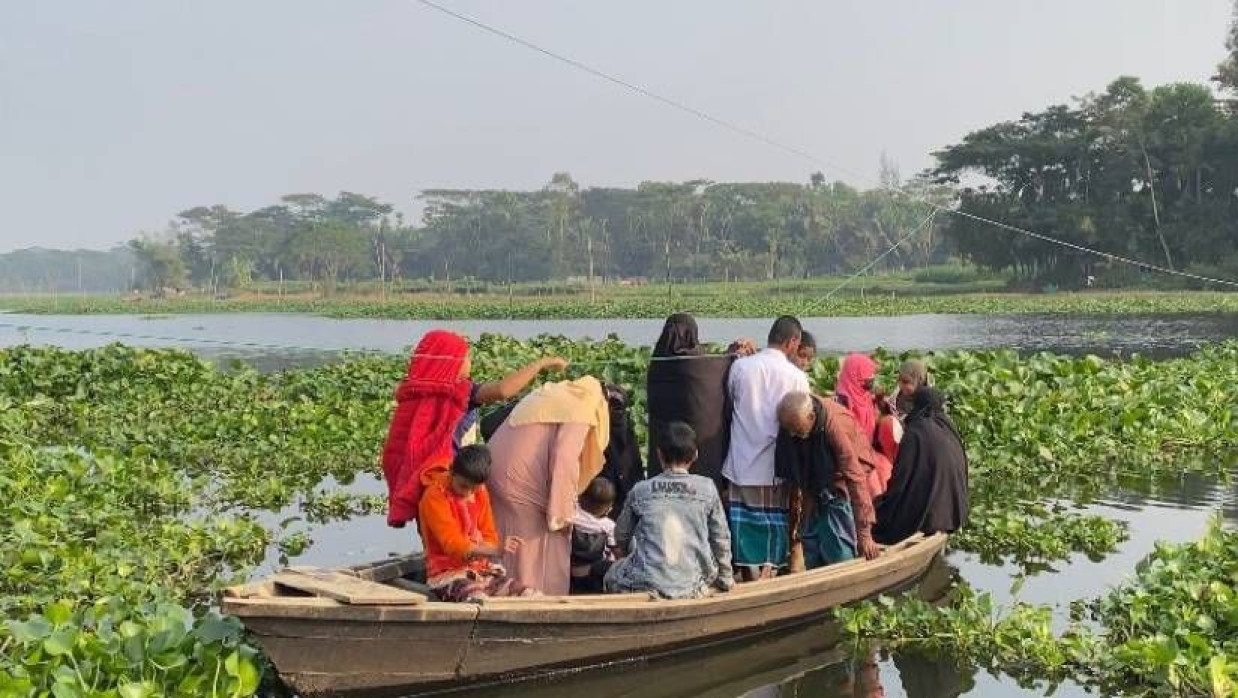 নৌকা দিয়ে নদী পার হচ্ছেন স্থানীয় লোকজন