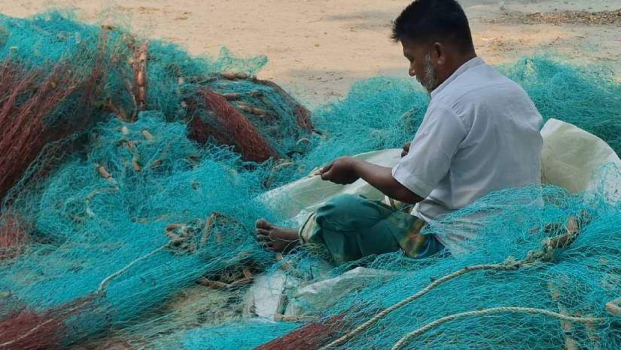 জাল মেরামত করছেন জেলে