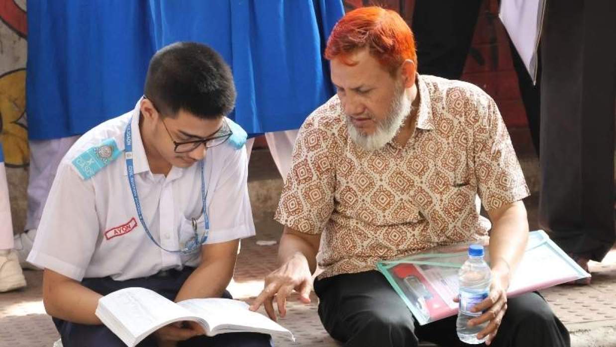পরীক্ষার্থীকে শেষ মুহুর্তের প্রস্তুতিতে সহযোগিতা করছেন অভিভাবক