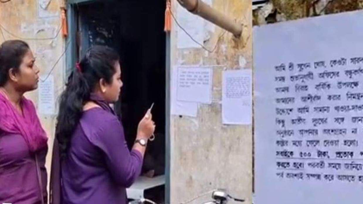পশ্চিমবঙ্গের চুঁচুড়া পুরসভার জলকল দফতরের কর্মীর সাটানো পোস্টার দেখছেন দুই নারী