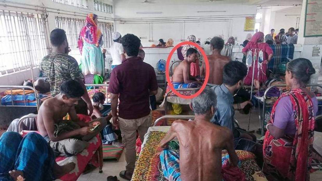 ডেঙ্গুতে আক্রান্ত রোগী ইসমাইল হোসেন মশারি টাঙানো ছাড়াই খোলা বেডে খালি গায়ে বসে আছেন (গোল চিহ্নিত)