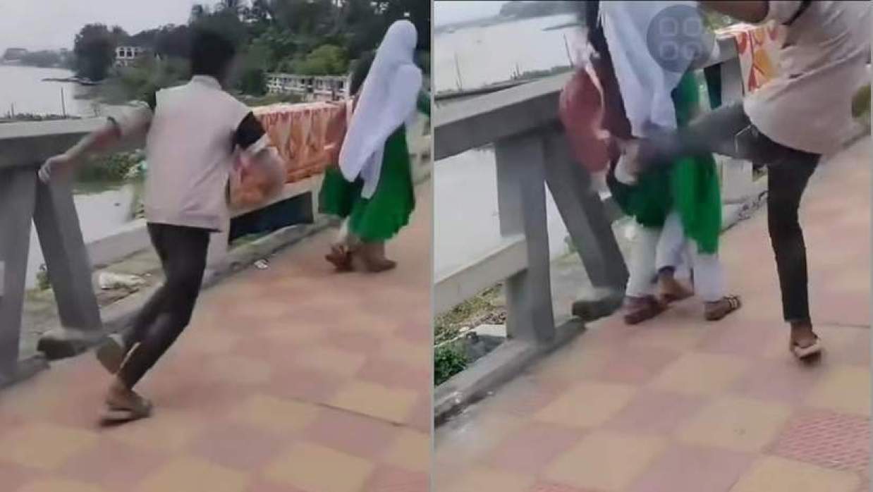 স্কুলড্রেস পরা এক ছাত্রীকে পেছন থেকে লাথি মারছে একটি ছেলে