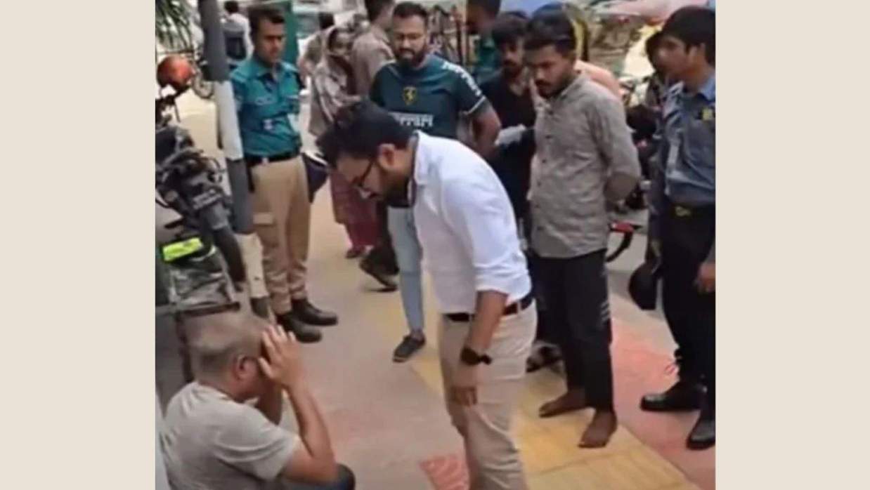 নিচে বসে থাকা ব্যক্তিকে মারধর ও কান ধরে ওঠবস করান সাদা শার্ট পরিহিত ব্যক্তি
