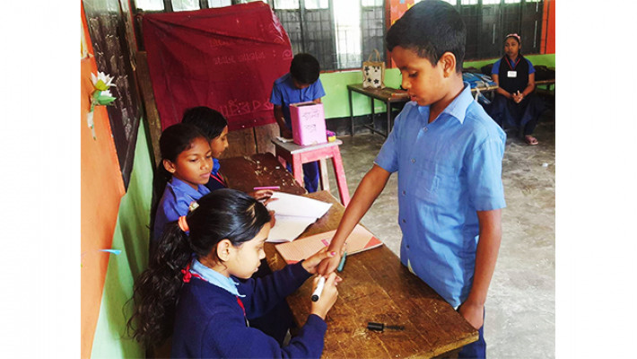 ভোটারের হাতে কালি দিচ্ছে নির্বাচনে দায়িত্বে থাকা ক্ষুদে শিক্ষার্থী