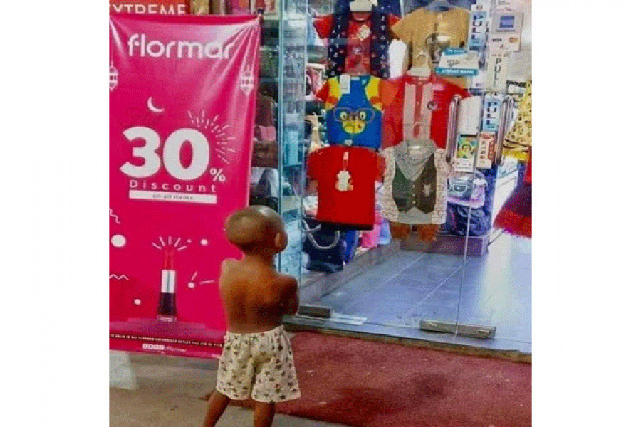 দোকানের বাইরে থেকে নতুন পোশাক দেখছেন শিশুটি