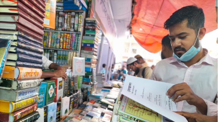 ইসলামি বই মেলায় বই হাতে এক ক্রেতা 