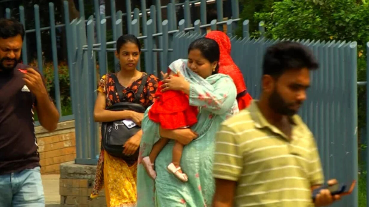 শিশুকে রোদ থেকে বাঁচানোর চেষ্টা করছেন অভিভাবক
