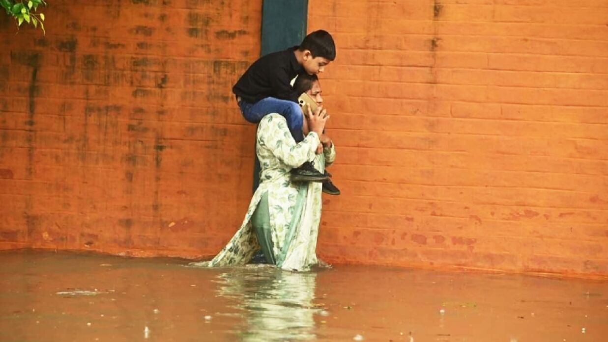 কোমর পানিতে মায়ের কাঁধে শিশু