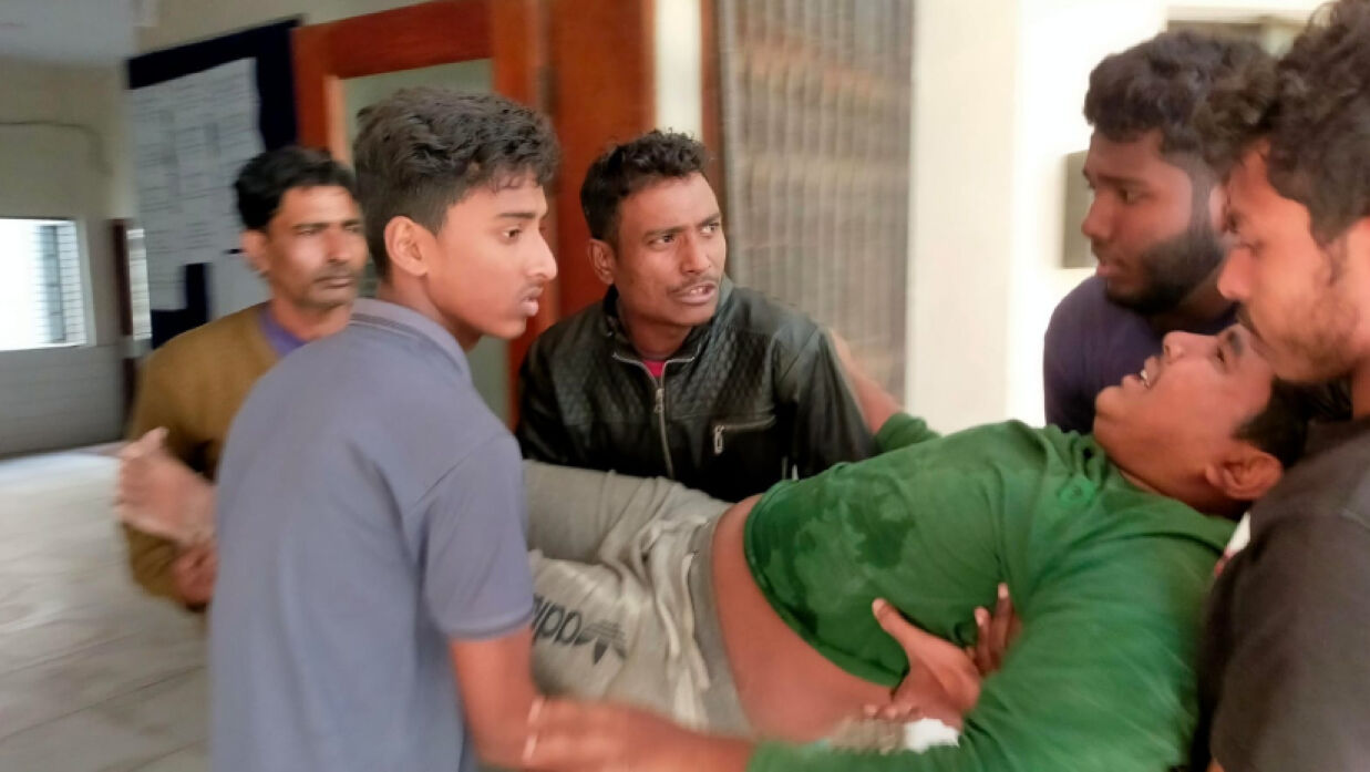 নির্মাণ শ্রমিক হাসানুর হাসানকে উদ্ধার করে নিয়ে যাচ্ছেন কয়েকজন