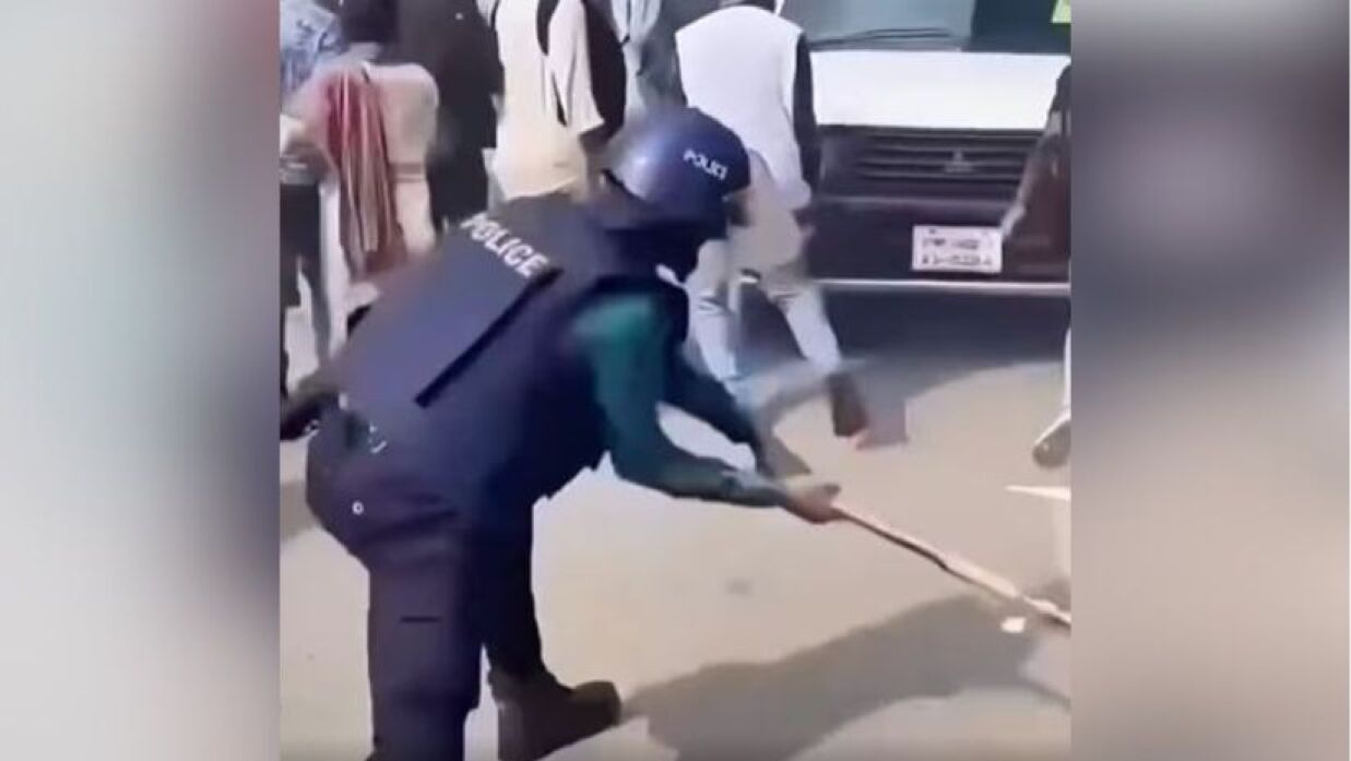 আন্দোলনকারীদের সরিয়ে দিতে সড়কের ওপরে আঘাত করছেন পুলিশ সদস্য