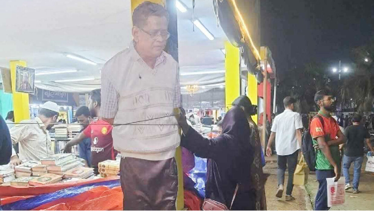বইমেলায় দড়ি দিয়ে বাঁধা হুমায়ুন আহমেদের ছবি সম্বলিত একটি প্ল্যাকার্ড