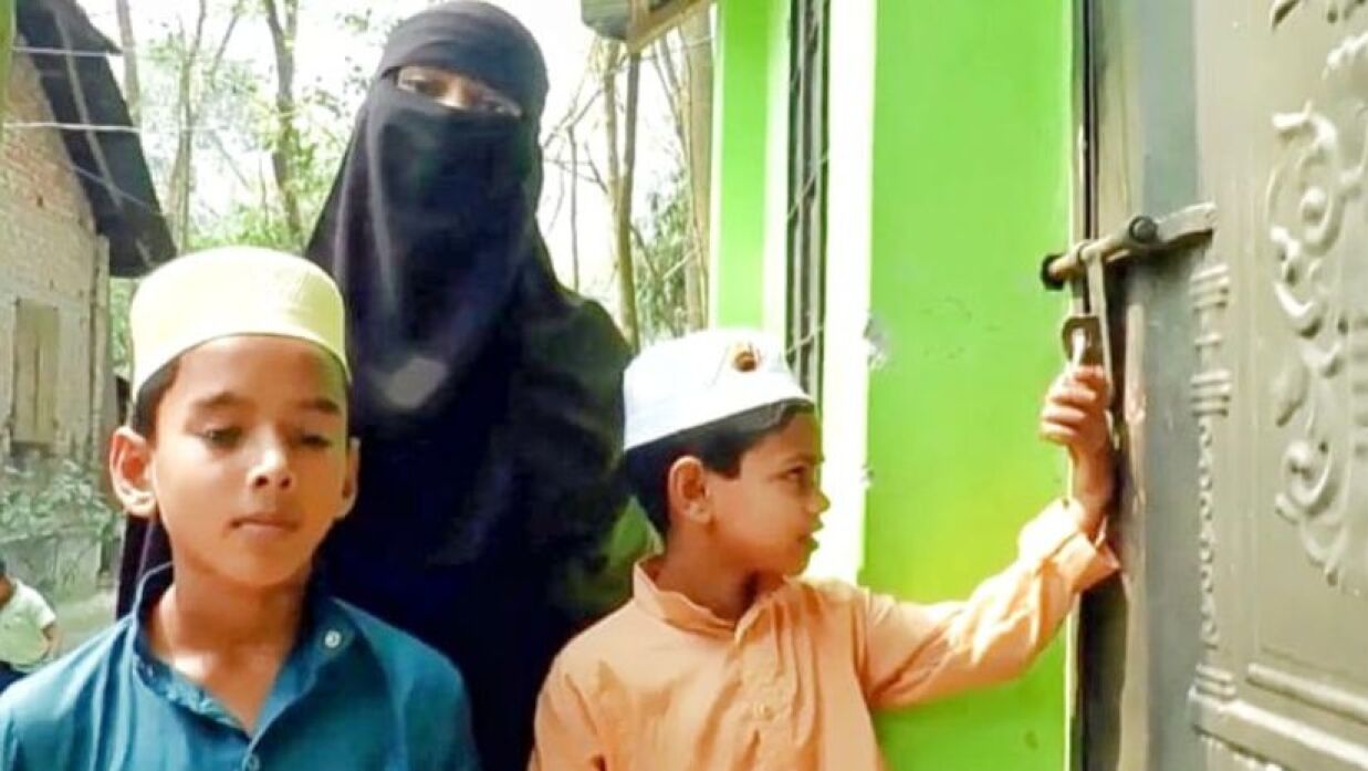 দুই সন্তানসহ ঘরের বাইরে দাঁড়িয়ে আছেন ভুক্তভোগী রাবিয়া আক্তার সুমি