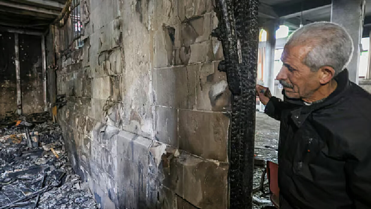 আংশিক পুড়ে যাওয়া আল–নাসর মসজিদ ঘুরে দেখছেন একজন ফিলিস্তিনি