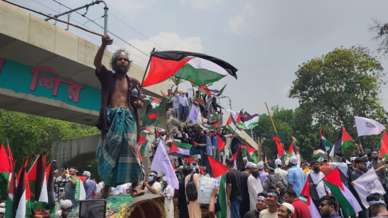 রাজু ভাস্কর্যের সামনে রিকশার ওপর দাঁড়িয়ে ফিলিস্তিনের পতাকা ওড়াছেন আনোয়ার হোসেন